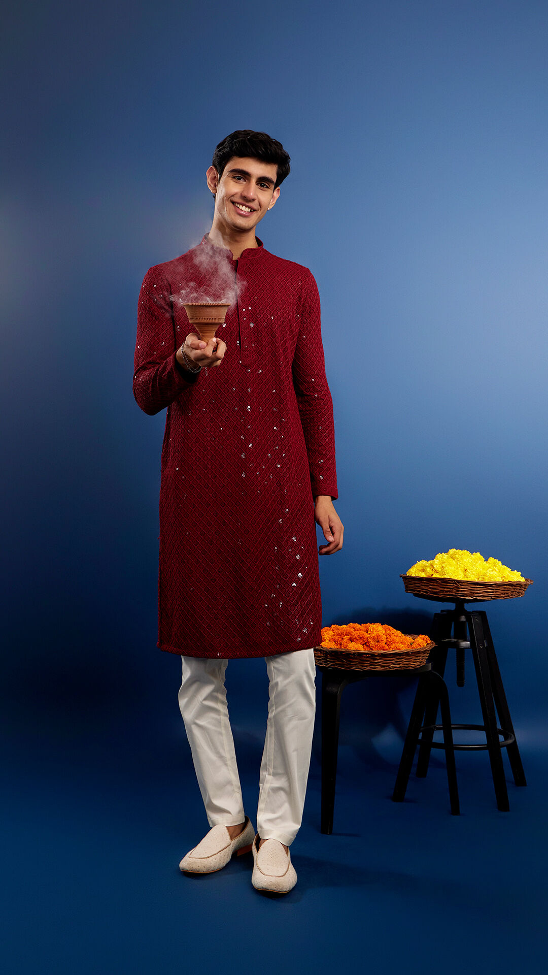 A young man in a traditional red kurta holding an incense burner as part of a Durga Puja ritual.